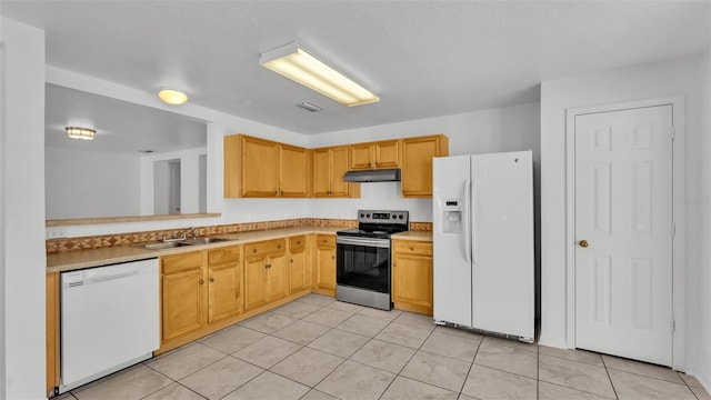 kitchen with light tile patterned floors, white appliances, light brown cabinetry, and sink