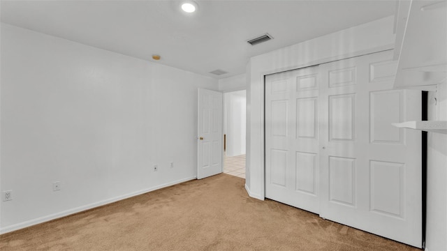 unfurnished bedroom with light colored carpet and a closet