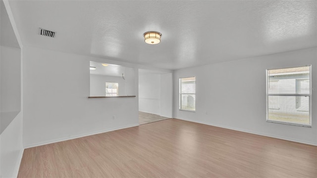 spare room with a textured ceiling and light hardwood / wood-style flooring