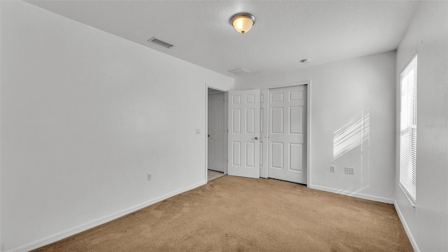 unfurnished bedroom with light carpet and a closet