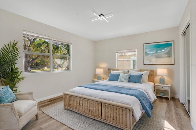 bedroom featuring light wood-type flooring, multiple windows, and baseboards