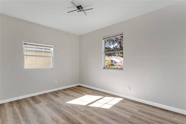 unfurnished room with plenty of natural light, baseboards, and wood finished floors