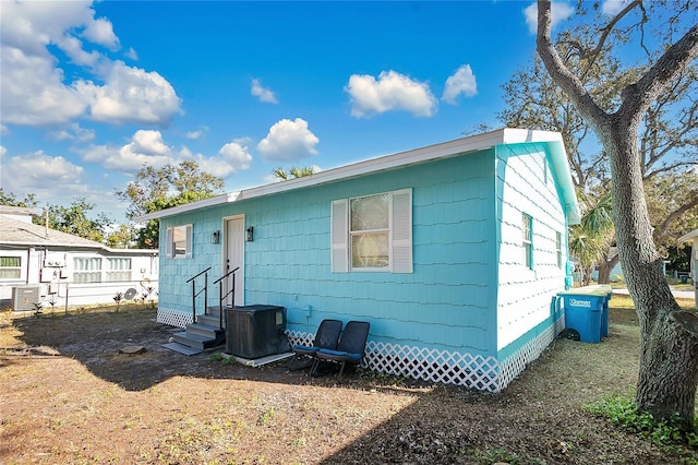 back of property with entry steps and central AC