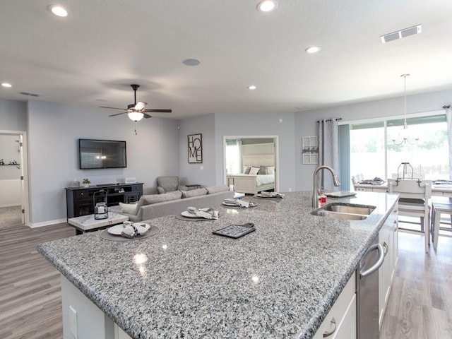 kitchen featuring white cabinets, a center island with sink, and sink