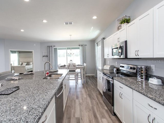 kitchen featuring light stone countertops, white cabinetry, sink, light hardwood / wood-style flooring, and appliances with stainless steel finishes