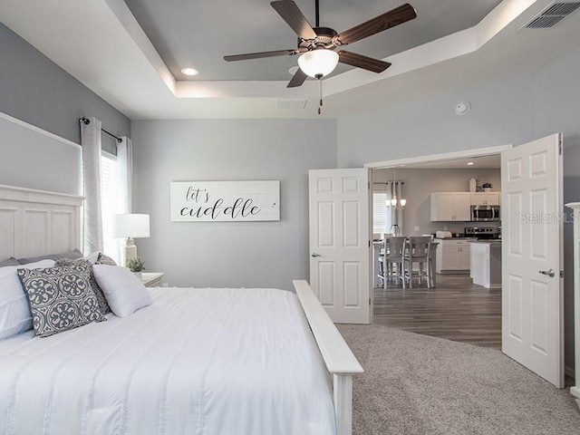 bedroom featuring dark hardwood / wood-style floors, a raised ceiling, and ceiling fan