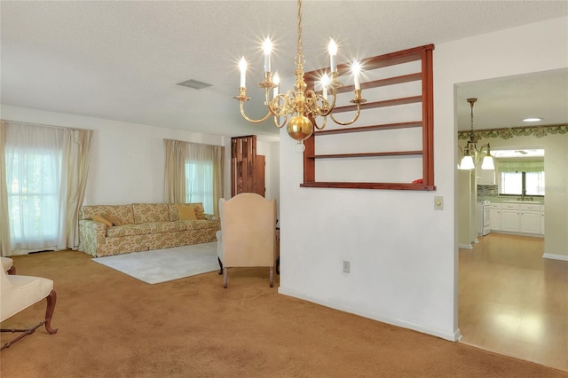 living room with carpet flooring, a chandelier, and a textured ceiling