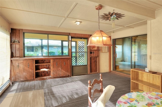 carpeted dining space with a wealth of natural light, wooden walls, and a baseboard radiator