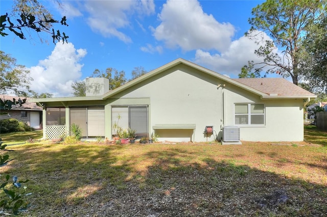 back of property with a lawn, a sunroom, and central AC