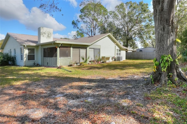 view of home's exterior with a lawn, a sunroom, and central AC unit