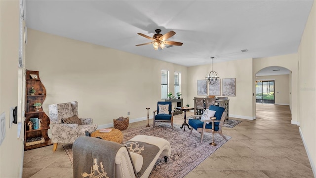 living room featuring ceiling fan with notable chandelier and a wealth of natural light