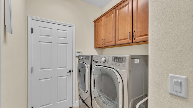 clothes washing area featuring cabinets and washing machine and clothes dryer