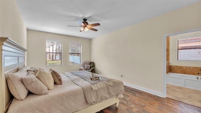 bedroom featuring ceiling fan, ensuite bath, and hardwood / wood-style floors