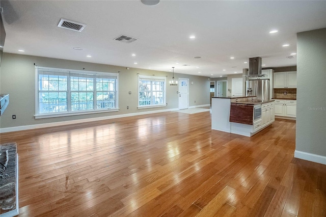 unfurnished living room with light hardwood / wood-style flooring and an inviting chandelier