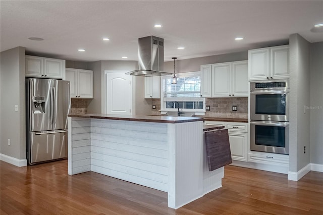 kitchen with island range hood, dark hardwood / wood-style flooring, white cabinets, and stainless steel appliances