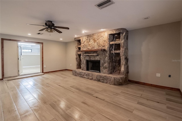 unfurnished living room with a stone fireplace, ceiling fan, and light hardwood / wood-style floors