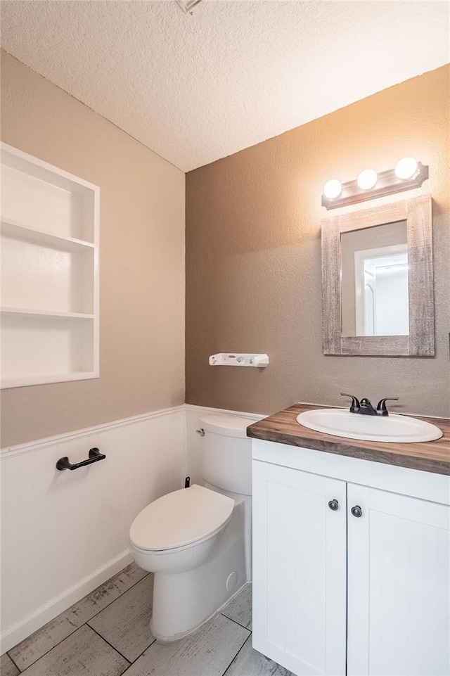 bathroom with vanity, a textured ceiling, and toilet