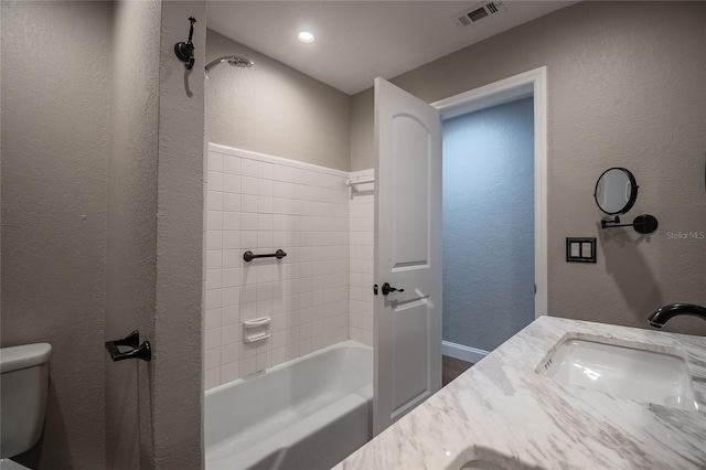 full bathroom with vanity, tiled shower / bath combo, and toilet