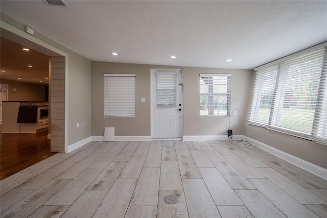 interior space with lofted ceiling, a textured ceiling, and light hardwood / wood-style flooring