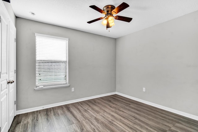 unfurnished room with a textured ceiling, ceiling fan, and dark wood-type flooring