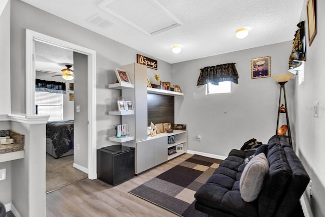 living room featuring ceiling fan, a healthy amount of sunlight, a textured ceiling, and light hardwood / wood-style floors