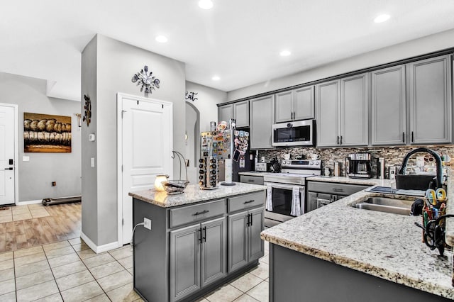 kitchen with gray cabinets, sink, an island with sink, and appliances with stainless steel finishes