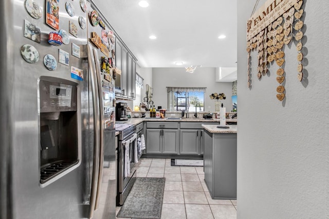 kitchen with sink, stainless steel appliances, light stone counters, gray cabinets, and light tile patterned floors