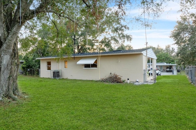 back of property with central AC and a lawn