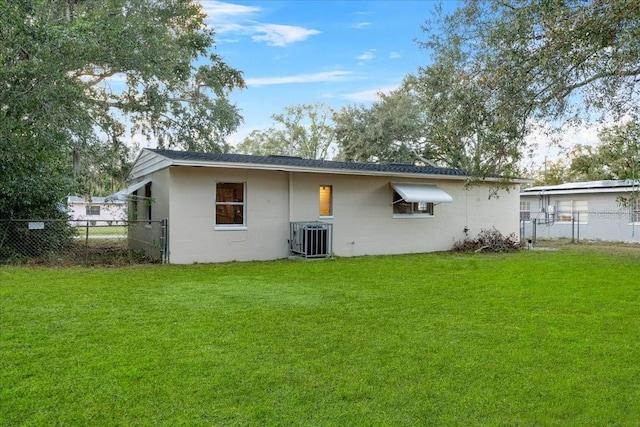 rear view of house featuring cooling unit and a lawn