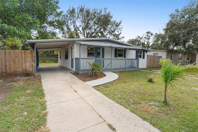 view of front of home featuring covered porch, a front lawn, and a carport