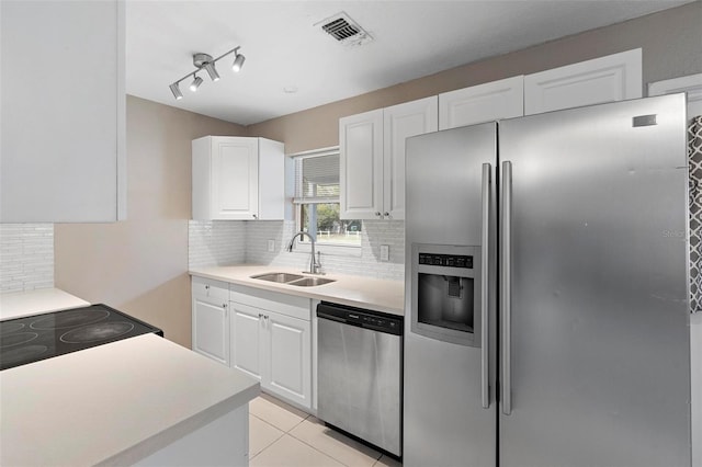 kitchen featuring white cabinetry, sink, stainless steel appliances, decorative backsplash, and light tile patterned flooring