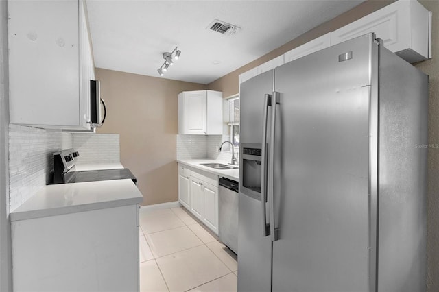 kitchen featuring sink, decorative backsplash, light tile patterned floors, appliances with stainless steel finishes, and white cabinetry