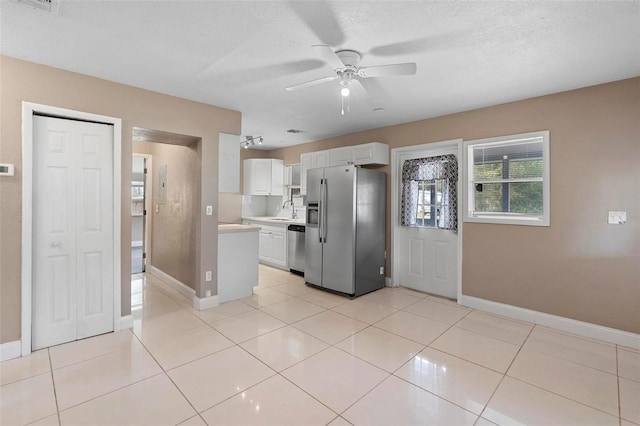 kitchen featuring ceiling fan, light tile patterned flooring, a textured ceiling, white cabinets, and appliances with stainless steel finishes