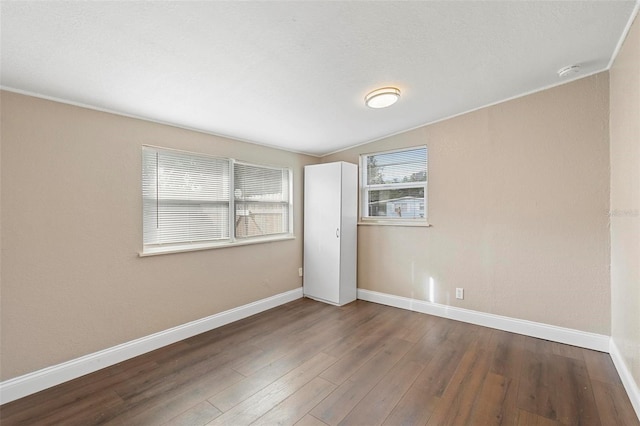 unfurnished bedroom with a textured ceiling, dark hardwood / wood-style floors, and lofted ceiling