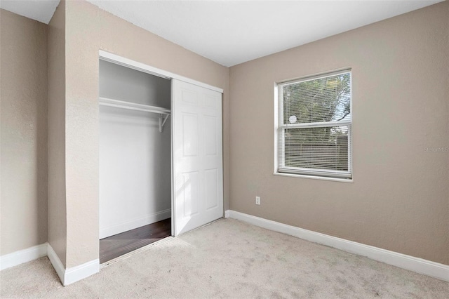 unfurnished bedroom with light colored carpet and a closet