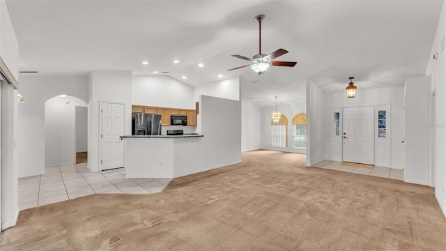 unfurnished living room with light colored carpet, high vaulted ceiling, and ceiling fan