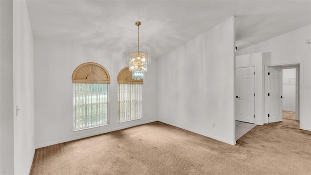 empty room featuring a chandelier, light colored carpet, and vaulted ceiling