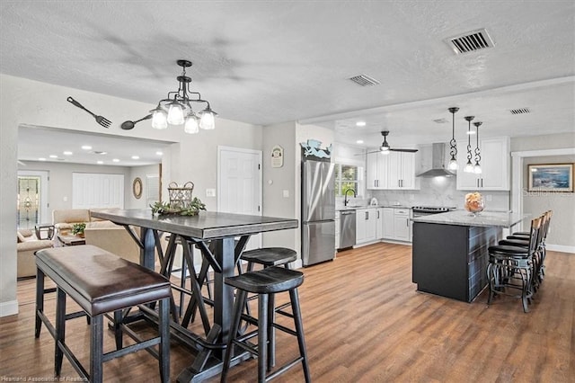 dining space with ceiling fan, sink, wood-type flooring, and a textured ceiling