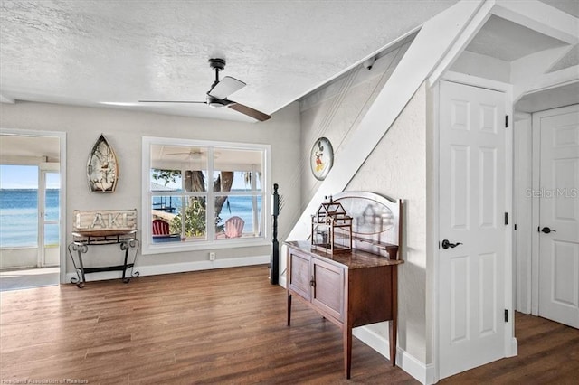 interior space featuring a textured ceiling, dark hardwood / wood-style floors, and a water view