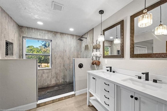 bathroom featuring hardwood / wood-style floors, vanity, and a tile shower