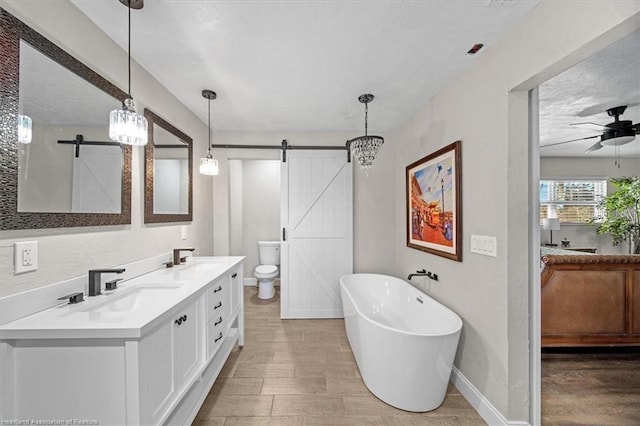 bathroom with a tub, ceiling fan, toilet, vanity, and hardwood / wood-style flooring