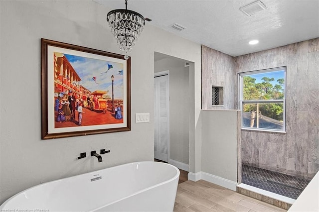 bathroom featuring plus walk in shower, hardwood / wood-style flooring, and an inviting chandelier