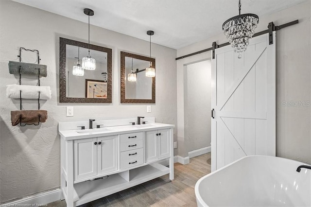 bathroom with a chandelier, hardwood / wood-style floors, vanity, and a tub