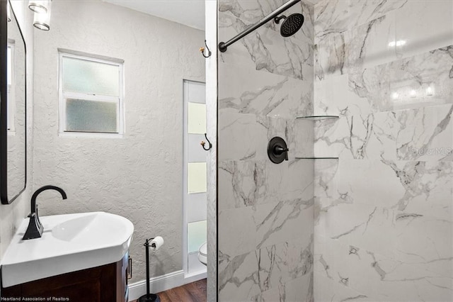 bathroom with vanity, toilet, wood-type flooring, and tiled shower