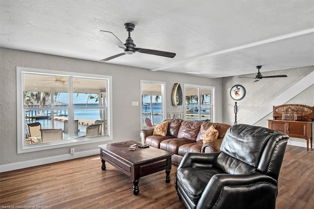 living room featuring wood-type flooring, a textured ceiling, a water view, and a healthy amount of sunlight