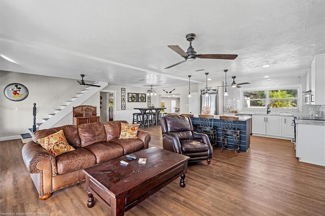 living room featuring hardwood / wood-style floors, ceiling fan, and sink