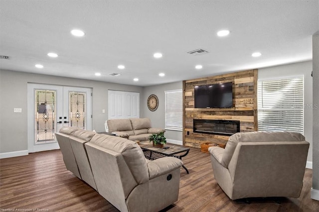 living room featuring a stone fireplace, dark hardwood / wood-style flooring, and french doors