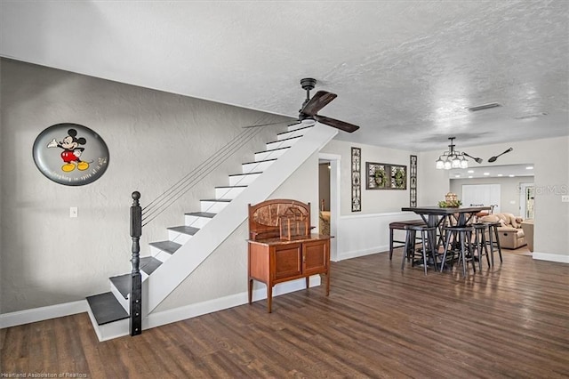 interior space featuring a textured ceiling, ceiling fan with notable chandelier, and dark hardwood / wood-style floors