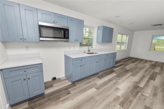 kitchen with blue cabinetry, sink, and light hardwood / wood-style flooring