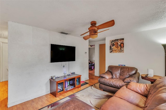 living room featuring ceiling fan, a textured ceiling, and light hardwood / wood-style flooring